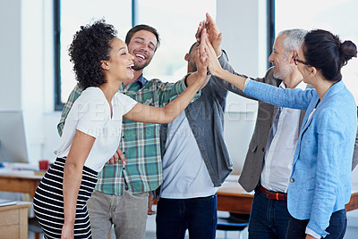 Buy stock photo Shot of a group of happy coworkers high-fiving while standing in an office