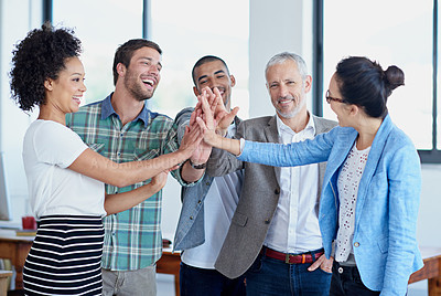 Buy stock photo Shot of a group of happy coworkers high-fiving while standing in an office