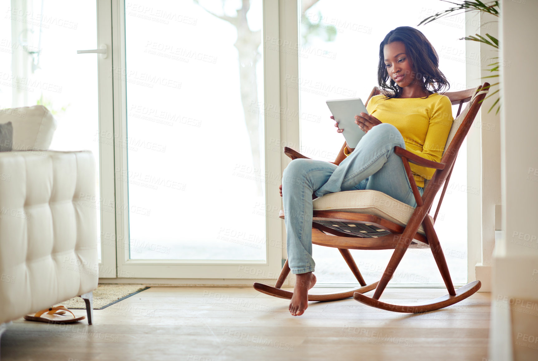 Buy stock photo Cropped shot of an attractive young woman using a digital tablet relaxing at home