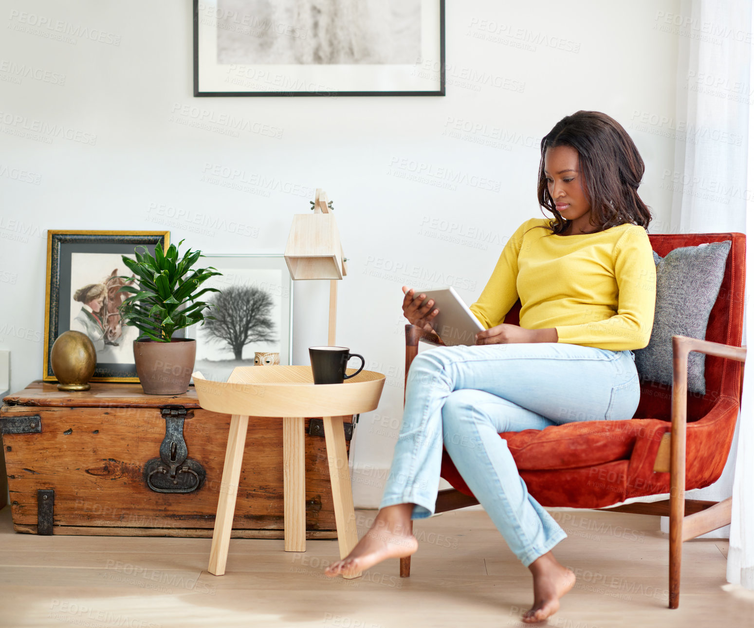 Buy stock photo Cropped shot of an attractive young woman using a digital tablet relaxing at home