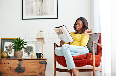 Buy stock photo Shot of a young woman relaxing at home with a magazine