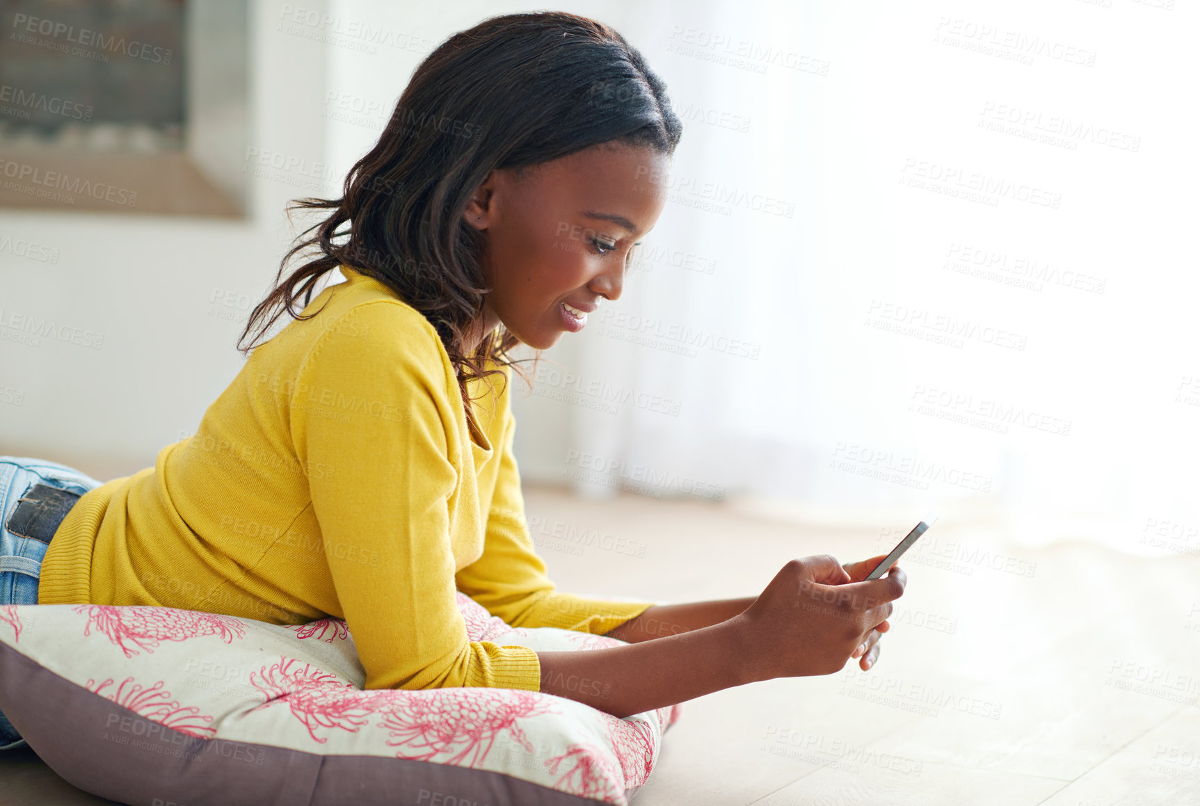 Buy stock photo Cropped shot of an attractive young woman texting while relaxing at home