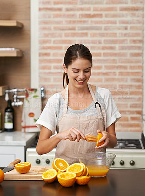Buy stock photo Woman, in kitchen and fresh orange juice in bowl for healthy drink, vitamin C or organic snack. Nutritionist, in apron and making delicious citrus liquid for natural treat, baking cake or new diet