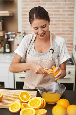 Buy stock photo Shot of an attractive woman preparing fresh orange juice in the kitchen
