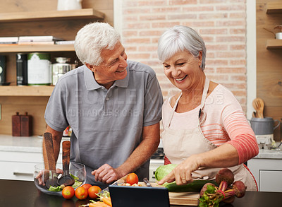 Buy stock photo Shot of a husband laughing with his wife as she prepares supper 