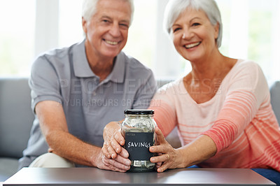 Buy stock photo Happy couple looking pleased with their savings so far