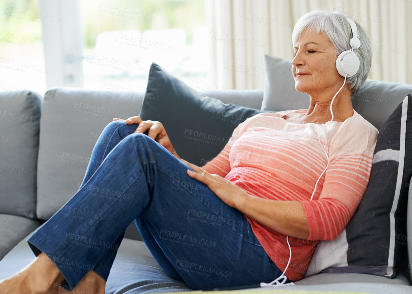 Buy stock photo Senior, woman and headphones on couch in house for relax, retirement and meditation, wellness and peace. Happiness, zen and podcast on couch in living room for self care, streaming and mindfulness