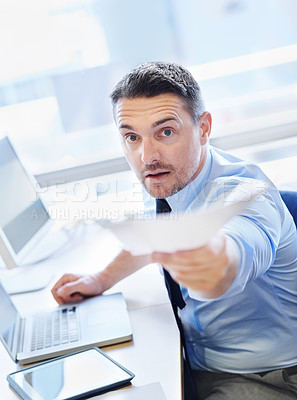 Buy stock photo Business man, giving document at desk in office with tech for share information or present ideas on project. Serious editor, laptop and tablet in workspace and give paperwork in deadline review      