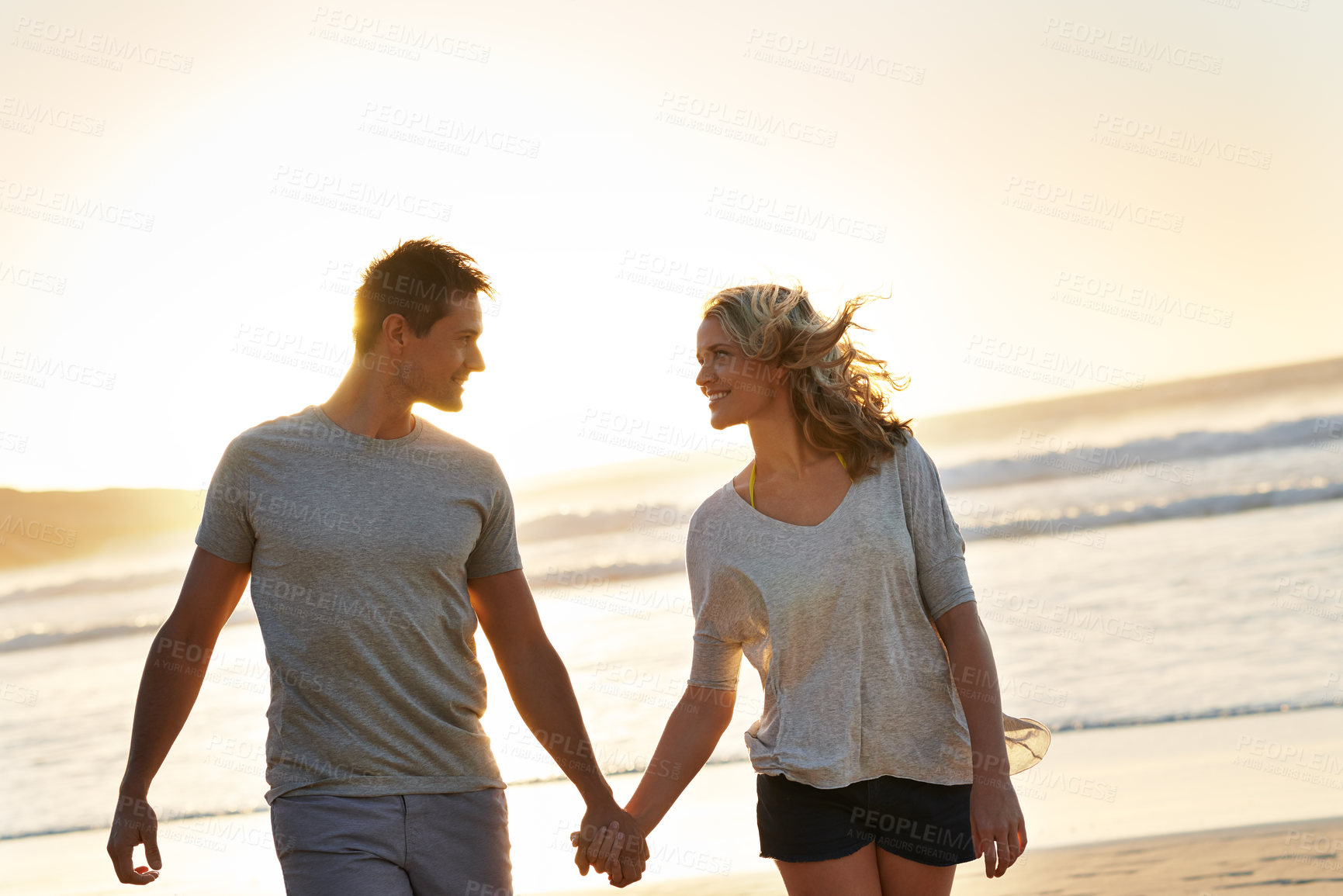 Buy stock photo Holding hands, smile and couple with love at beach, ocean and sea for affection, bonding or to relax. People, partners and romance for care together on vacation, holiday and travel in Australia