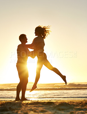 Buy stock photo Lifting, sunset and couple with love at beach, ocean or sea for affection, bonding or for fun with soulmate. People, sunrise and romance for care together on vacation, holiday and travel in Australia