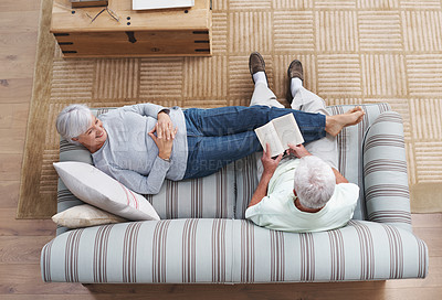 Buy stock photo A senior man reading to his wife as she she lies on the couch
