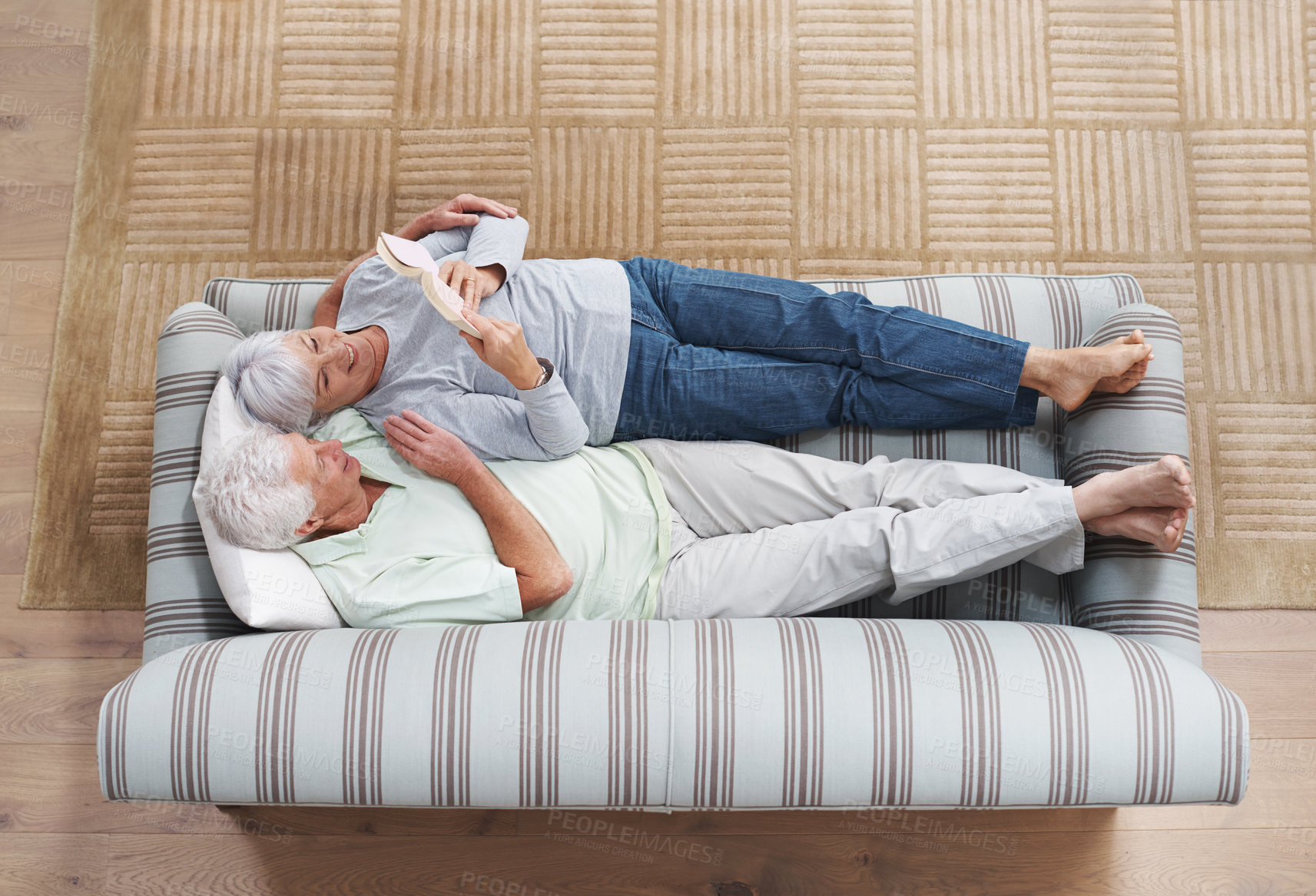 Buy stock photo Top view, senior couple and reading book on sofa in living room for story, knowledge and relax in home. Retirement,  elderly man and woman lying on couch for love, information and bonding together