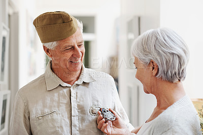 Buy stock photo Military, medal and honor with a senior couple in their home, feeling nostalgic about army service. War hero, award or memory and a mature man soldier in a house with his wife, feeling patriotic