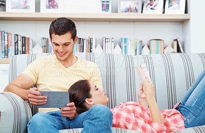 Buy stock photo A young couple relaxing at home on the sofa