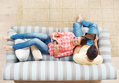 Buy stock photo Happy couple, home and relax above with sofa for reading, entertainment or information on book or tablet. Top view of man watching on technology with woman enjoying novel for holiday weekend together