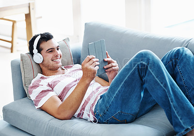 Buy stock photo Happy, headphones and man with tablet on sofa for online streaming, movie and watching video. Relax, smile and male person with technology at home for network, subscription or connectivity on weekend