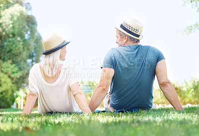Buy stock photo Rear view of a mature couple looking at each other while sitting on the grass