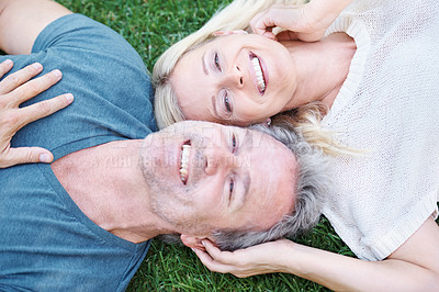 Buy stock photo A mature couple lying on the grass and looking up at you happily