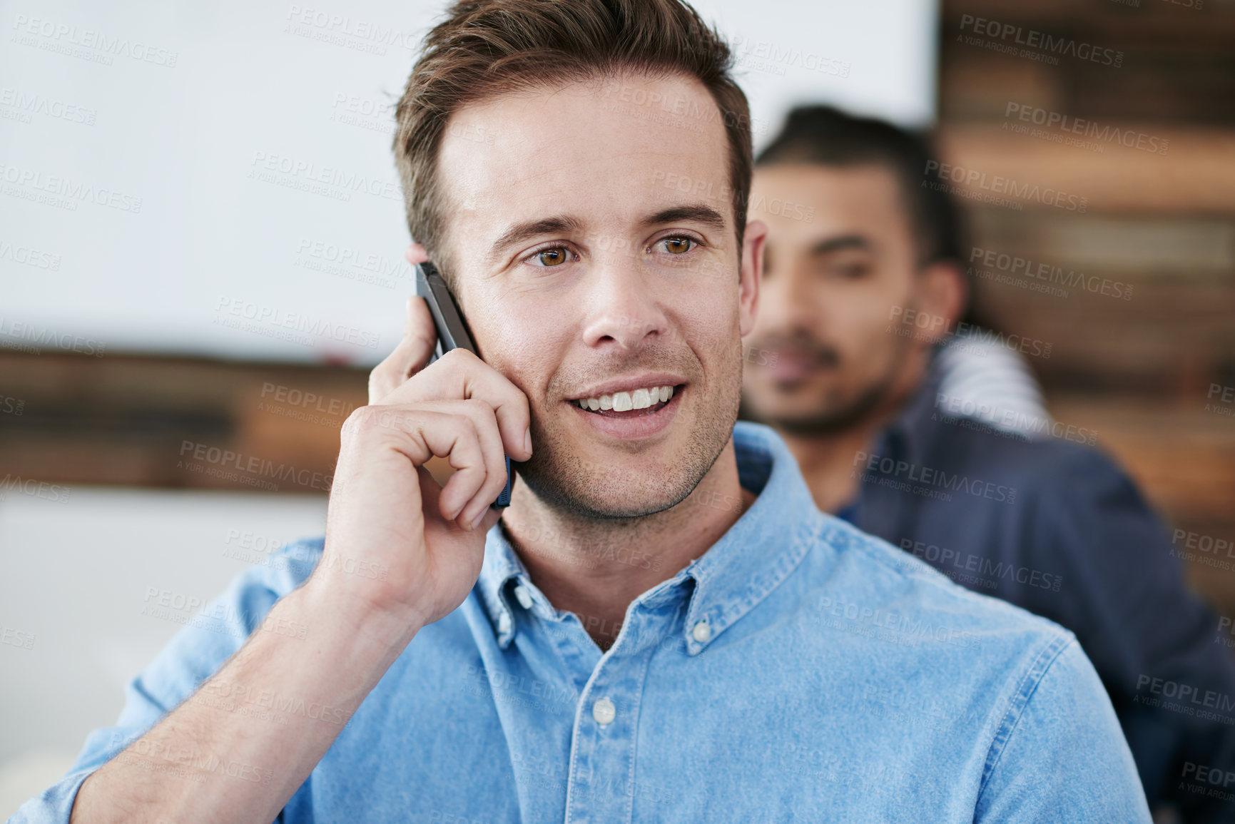 Buy stock photo Happy man, phone call and meeting with team for conversation, communication or chat at office. Male person or creative employee with smile on mobile smartphone for discussion or startup in boardroom