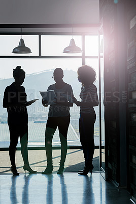 Buy stock photo Silhouette shot of female coworkers talking while standing in front of a window in an office