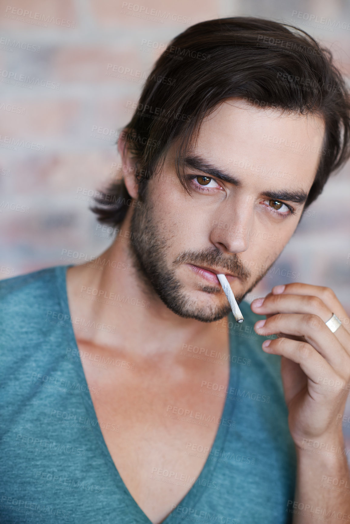 Buy stock photo Brick wall, portrait and man smoking cigarette, tobacco and 420 to relax on background. Nicotine, serious face and addiction to marijuana, weed and cbd for cannabis drug abuse problem in Germany