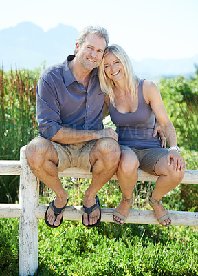 Buy stock photo A happy mature couple sitting on a fence outdoors