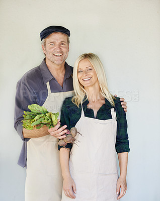 Buy stock photo A happy couple in aprons holding a bunch of beetroot