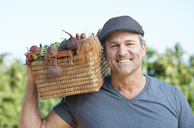 Buy stock photo A smiling mature farmer holding a basket of fresh produce