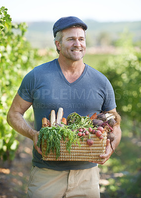 Buy stock photo A smiling mature farmer holding a basket of fresh produce