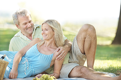 Buy stock photo A smiling husband and wife enjoying a leisurely picnic in the park
