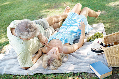 Buy stock photo A relaxed husband and wife lying down on a blanket as they enjoy a leisurely picnic in the park