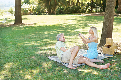 Buy stock photo A relaxed husband and wife lying down on a blanket as they enjoy a leisurely picnic in the park