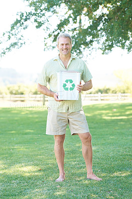 Buy stock photo A man standing in a park holding a recycling bin while smiling at the camera