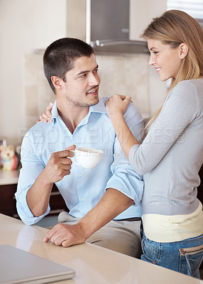 Buy stock photo A happy couple in their kitchen looking at each other lovingly 