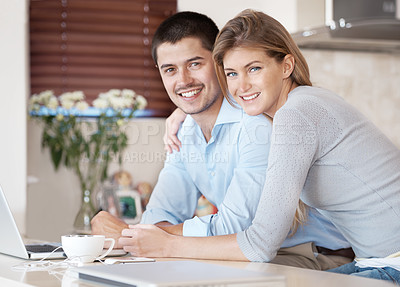 Buy stock photo Portrait of a smiling couple sitting in their kitchen with a laptop in front of them