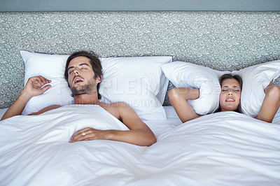 Buy stock photo Woman, stress and man snore in bed, sleeping and annoying noise or pillow to cover ears in home. Couple, block sound and audio from wife nap or dreaming, insomnia and frustrated or exhausted rest