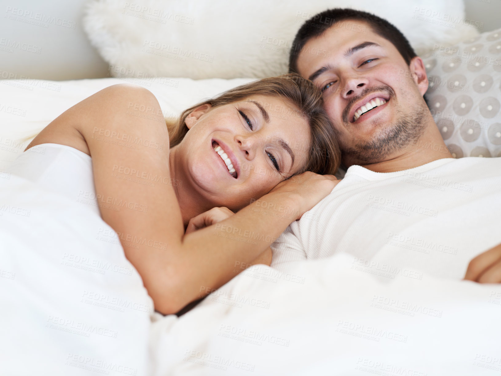 Buy stock photo Smiling young couple lying in bed together 