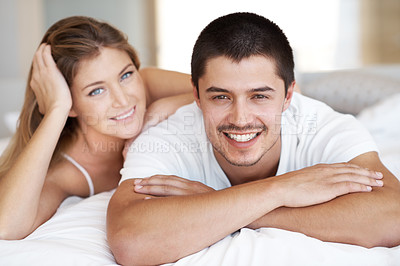 Buy stock photo Attractive young couple lying in bed together with broad smiles