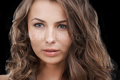 Buy stock photo Closeup of a beautiful woman touching her face isolated on studio background. Young female model with brown brunette curly hair and flawless clear glowing skin promoting skincare and beauty concept