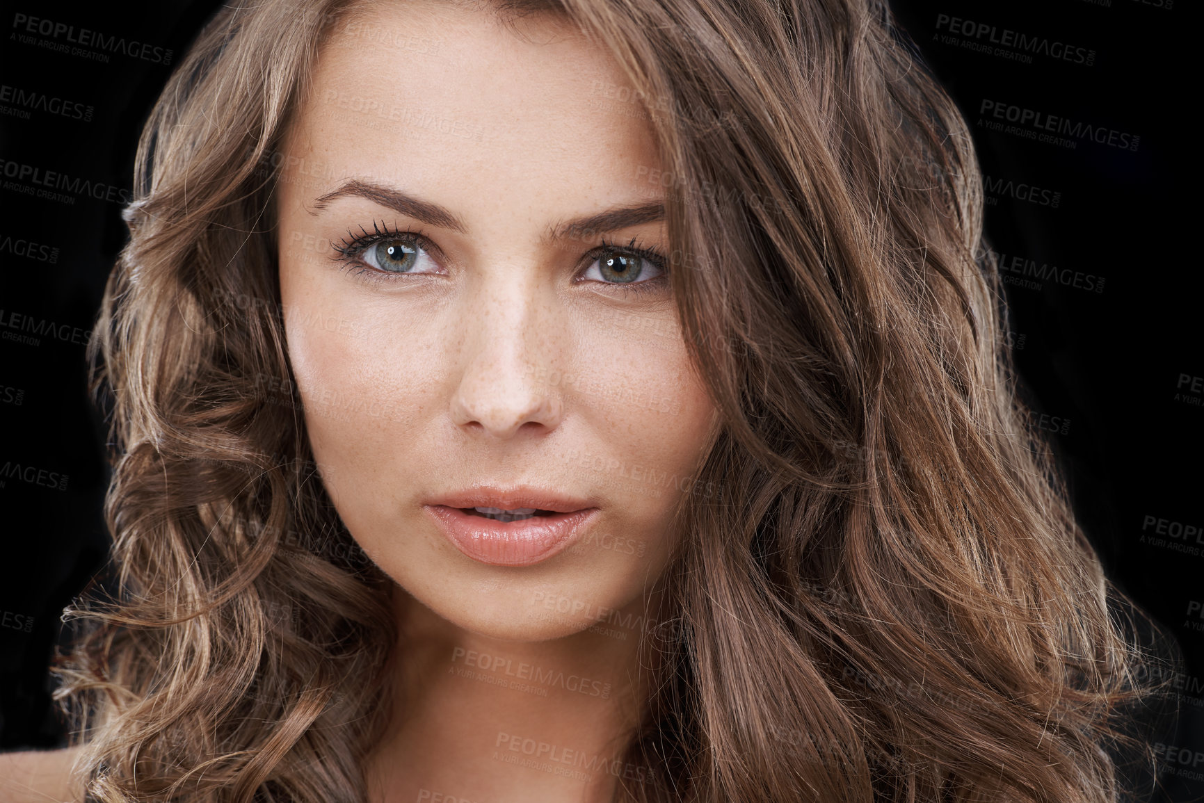 Buy stock photo Closeup of a beautiful woman touching her face isolated on studio background. Young female model with brown brunette curly hair and flawless clear glowing skin promoting skincare and beauty concept