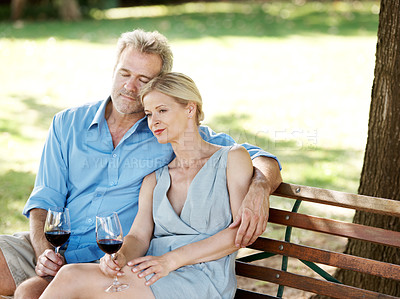 Buy stock photo Loving mature couple drinking wine together while outdoors in a park