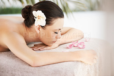 Buy stock photo A beautiful young woman lying on a massage table surrounded by rose petals