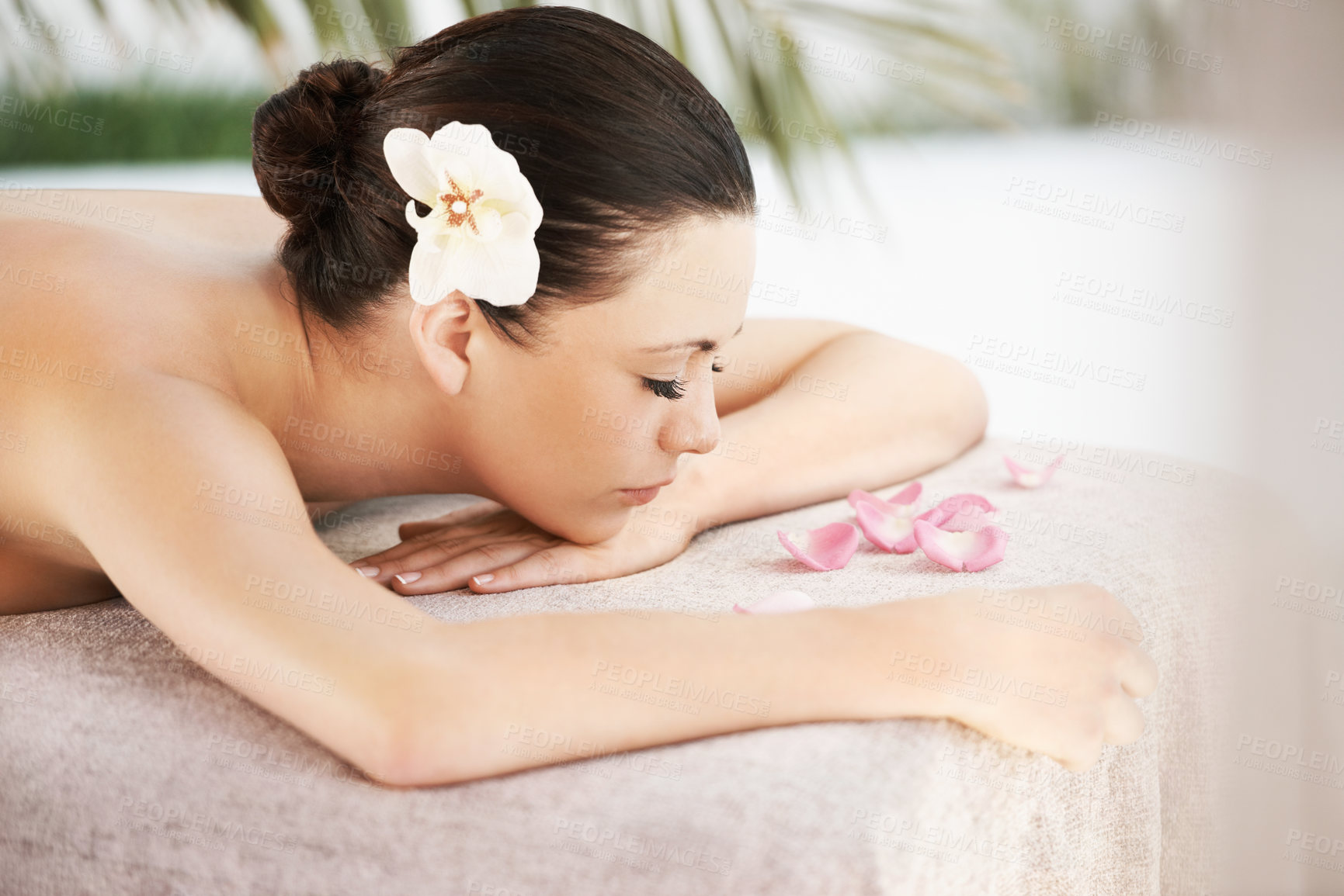 Buy stock photo A beautiful young woman lying on a massage table surrounded by rose petals