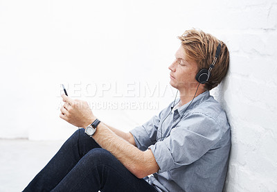 Buy stock photo Floor, man and smartphone with headphone for music, radio podcast and streaming online for playlist. Indoor, male person and cellphone for mobile application, song and audio track to relax by wall