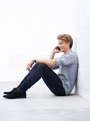 Buy stock photo Floor, man and phone call with smile for communication, chatting and talking with contact. Indoor, male person and mobile for conversation, laughing and networking with connection during break