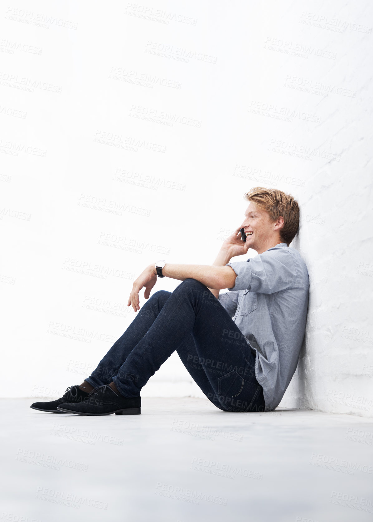 Buy stock photo Man, phone call and floor with space by wall with smile, communication and talk at startup. Young businessman, entrepreneur and sitting for conversation on smartphone with mockup at small business