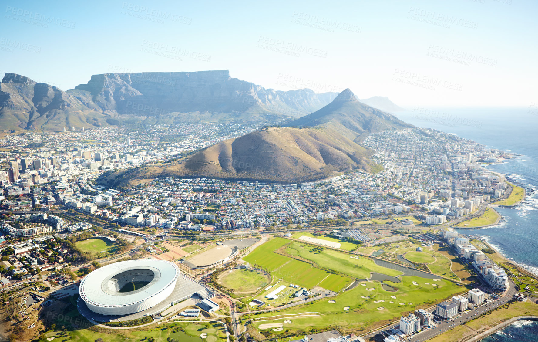 Buy stock photo Mountain, buildings and drone of landscape in nature for travel destination in city with blue sky. Infrastructure, stadium and aerial view of scenic green environment by sea for tourism in Cape Town.