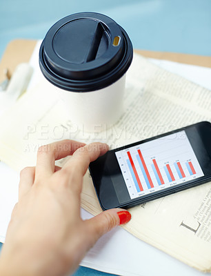 Buy stock photo Hand holding smartphone with bar chart on screen with disposable cup, pen, newspaper and clipboard