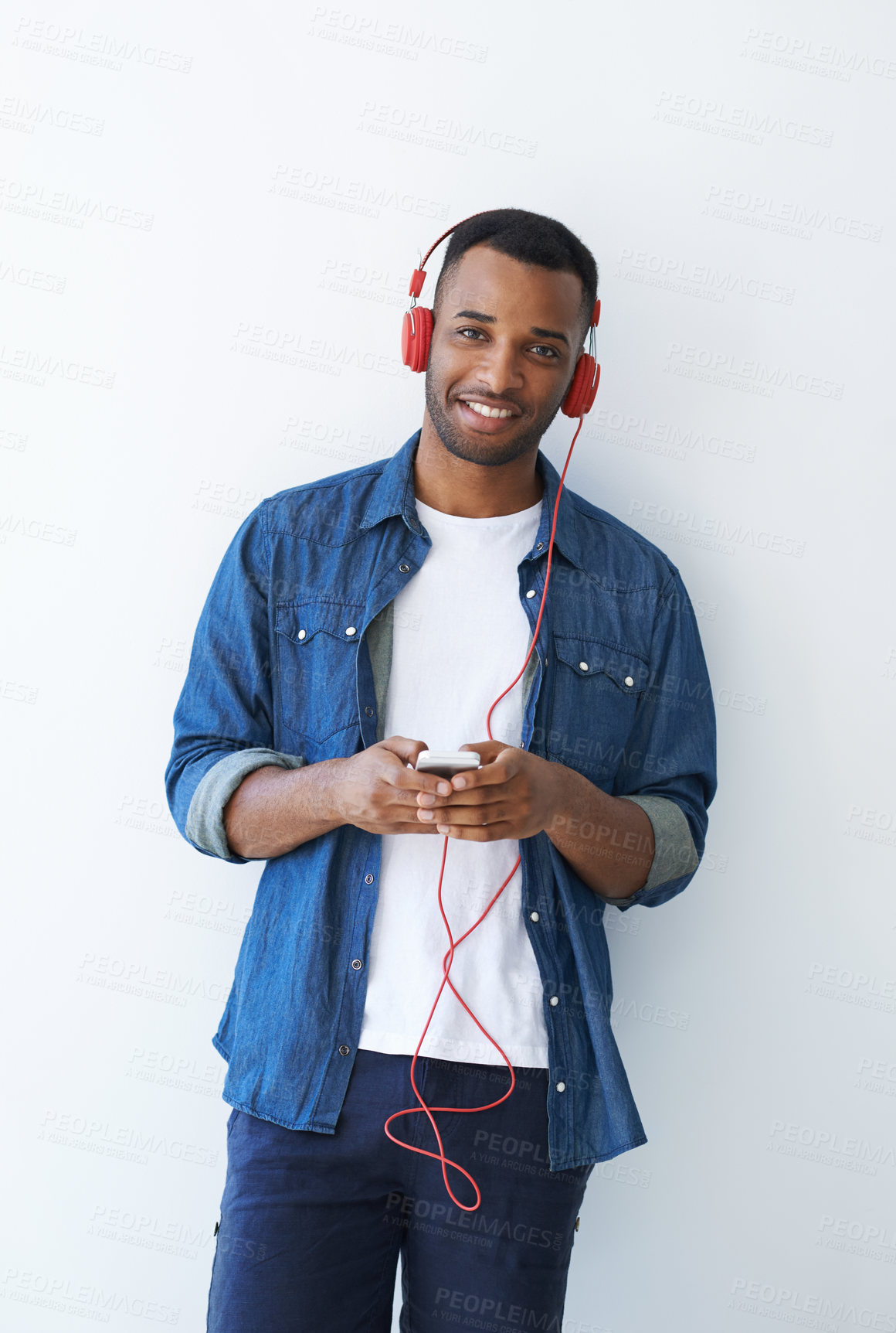 Buy stock photo Black man, phone and headphones with streaming by wall for portrait, happy and subscription on web. White background, smartphone and audio tech with search for music, listen and sound on mobile app