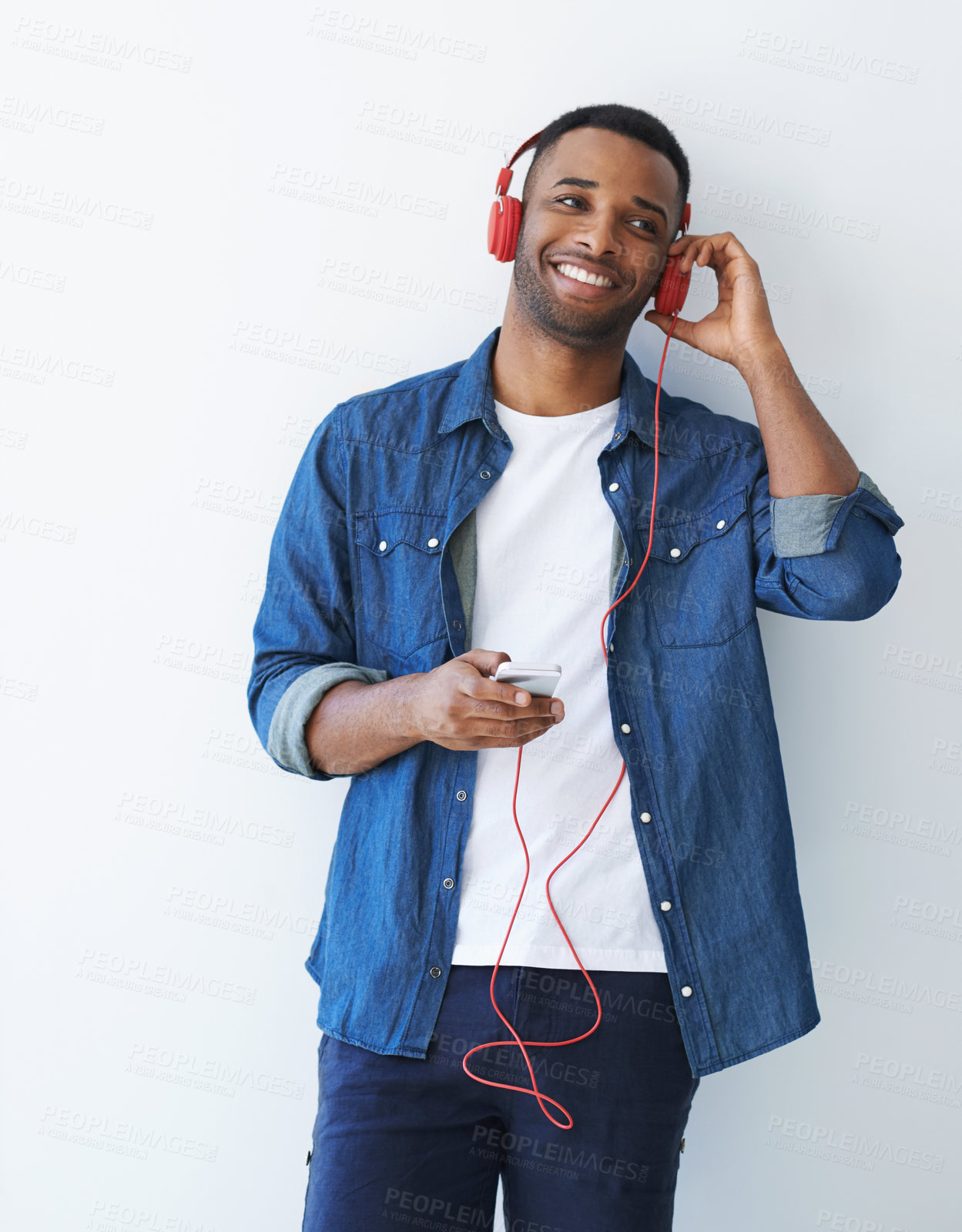 Buy stock photo Man, smartphone and headphones with music by wall for choice, streaming or remote work in home. Playlist curator, person and audio analysis for sound, mock up space and review for song distribution